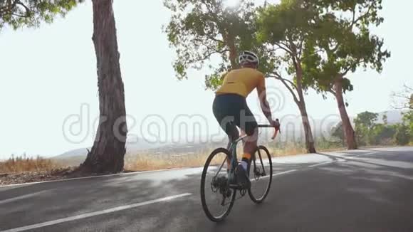 骑自行车的人沿着一条路上山后景夏日慢动作视频的预览图