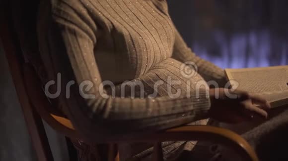 孕妇正在看书坐在黑暗的房间里的摇椅上视频的预览图