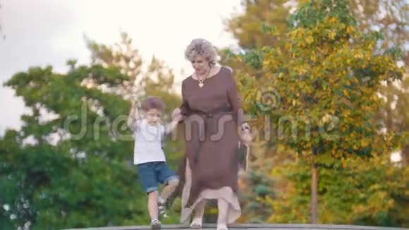 有魅力的祖母和孙子手牵着手走在公园的楼梯上视频的预览图