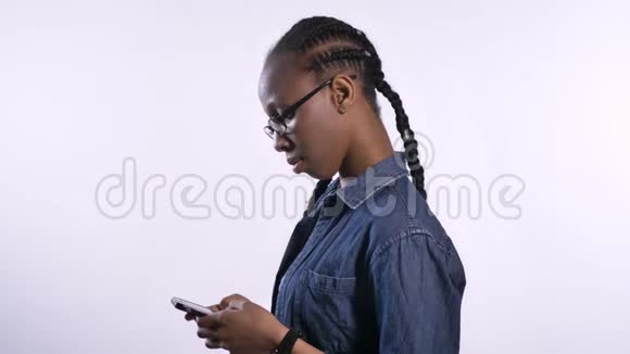 年轻漂亮的非洲裔美国妇女戴着眼镜在电话里发短信看着相机黑色模特的简介视频的预览图