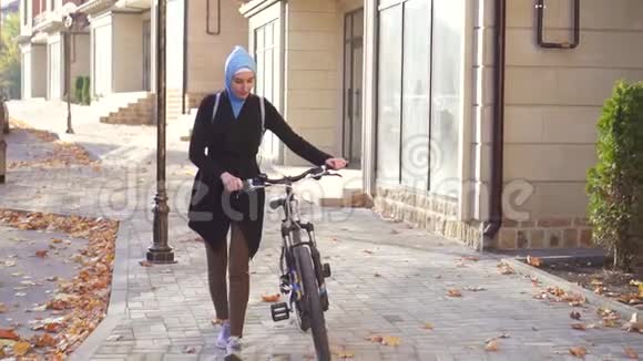 穆斯林妇女戴着头巾骑着自行车在城里慢悠悠视频的预览图