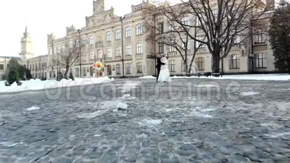 冬季婚礼新婚夫妇穿着婚纱走在白雪覆盖的公园里背景是视频的预览图