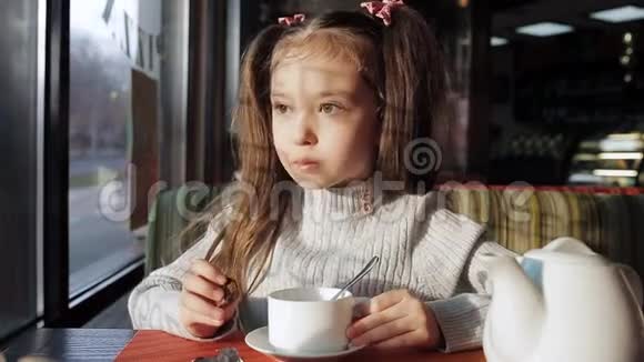 可爱的小女孩用糖果喝茶坐在窗边做着梦视频的预览图