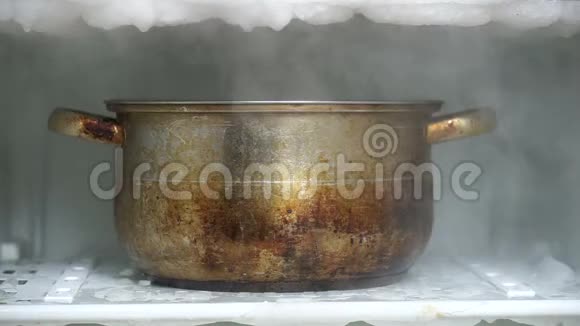 用盛满热水的厨房大锅解冻冰箱视频的预览图