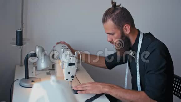 漂亮的时髦大胡子裁缝在自己的设计工作室里缝制时髦的衣服视频的预览图