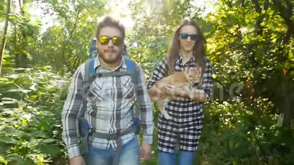 年轻夫妇带着他们的猫和背包在森林里旅游及远足概念视频的预览图