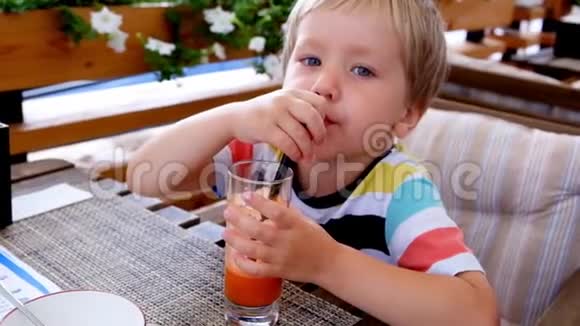 小可爱的男孩在咖啡馆喝胡萝卜鲜汁关门视频的预览图