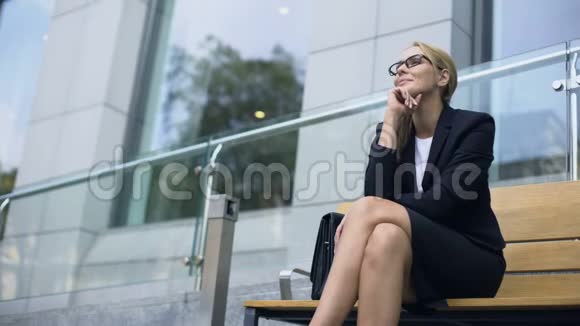女企业家坐在长凳上微笑着对成功的一天感到高兴视频的预览图
