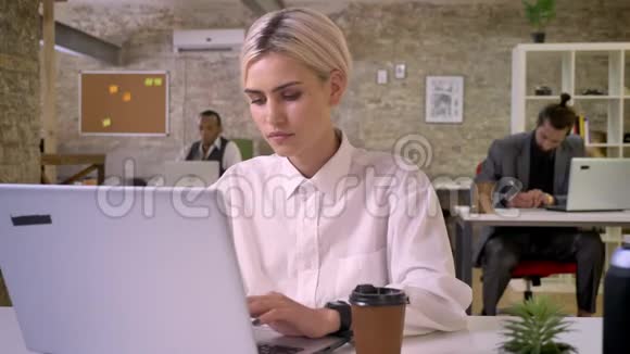 年轻快乐的女商人正在办公室里用笔记本电脑打字喝着咖啡同事们正在与科技建立联系视频的预览图