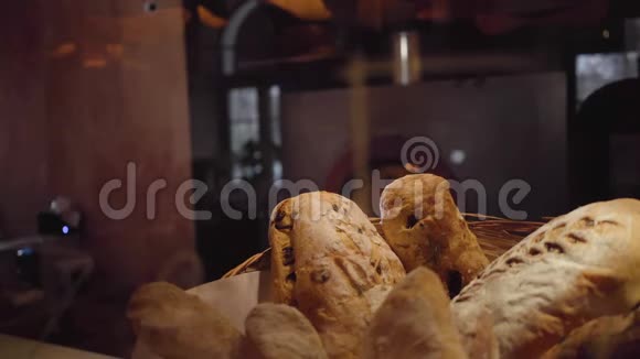 新鲜出炉的面包放在篮子里摆在现代餐厅的桌子上有燃烧的烤箱视频的预览图