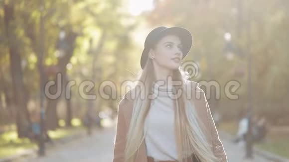 迷人的女孩在浪漫的外观带着黑色帽子走在公园的小巷看着相机给了惊人的视频的预览图