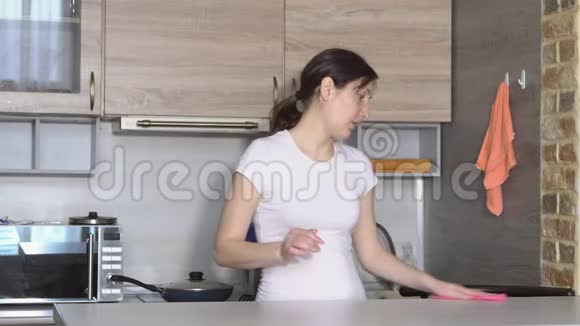 年轻的黑发女人在厨房打扫卫生视频的预览图
