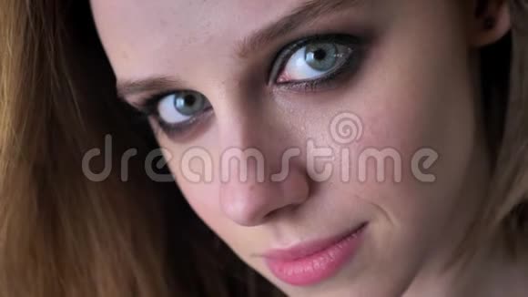 年轻迷人的女孩的脸烟雾般的眼睛盯着相机模糊的背景视频的预览图