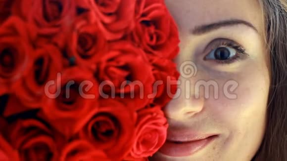 美丽的女人微笑着嗅着红玫瑰的花香视频的预览图