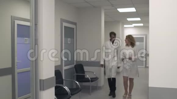 两位医生沿着医疗中心的走廊走着交流着视频的预览图