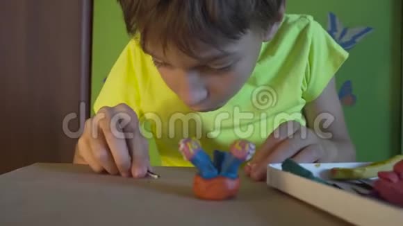 男孩坐在书桌前用彩色塑料雕刻图形培养儿童良好的运动技能视频的预览图