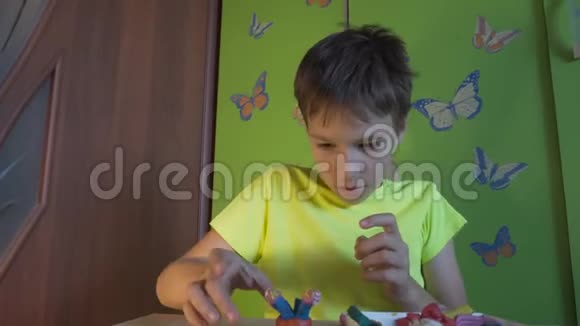 男孩坐在书桌前用彩色塑料雕刻图形培养儿童良好的运动技能视频的预览图