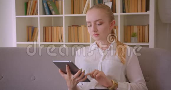 用平板电脑拍摄年轻漂亮的白种人金发女学生的特写肖像并用绿色屏幕拍摄视频的预览图