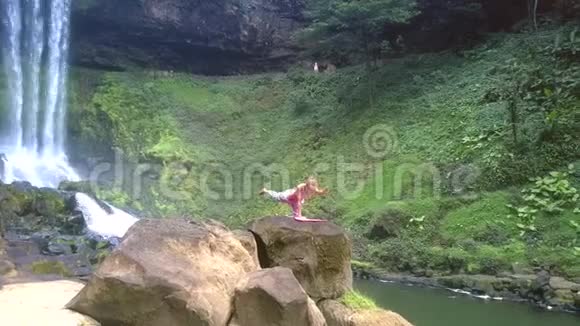 女人站在公园瀑布旁的石头上视频的预览图