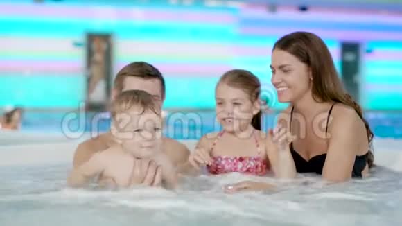 年幼的父母和孩子在游泳池里玩耍视频的预览图