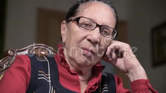一个戴着眼镜的老年沉思的女人在室内坐着思考靠在手臂上的肖像老年妇女80岁视频的预览图