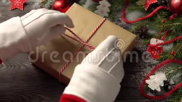 圣诞老人的手在针叶树树枝附近绑礼物视频的预览图
