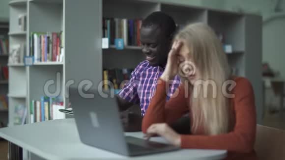 一个漂亮疲惫的女孩带着笔记本电脑和她的非裔美国朋友视频的预览图
