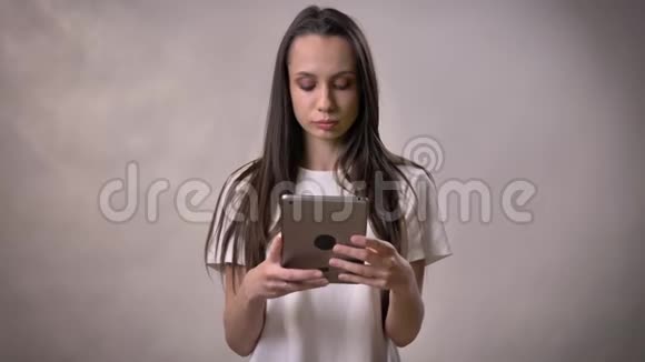 年轻的黑发女孩正在展示绿色的平板电脑屏幕交流理念灰色背景视频的预览图