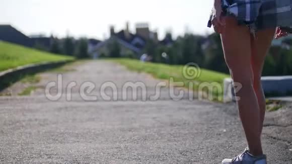 年轻女孩骑在滑板上的空路上后视视频的预览图