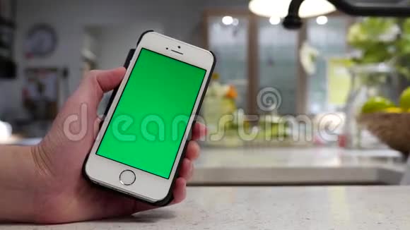 女人拿着绿色屏幕iphone和模糊的餐厅视频的预览图