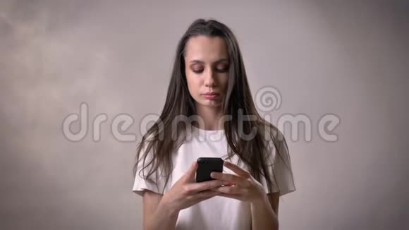 年轻的黑发女孩正在展示绿色的智能手机屏幕如标志沟通概念灰色背景视频的预览图