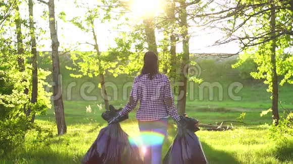 公园里穿着塑料垃圾袋的女志愿者在日落时分视频的预览图