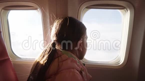 一个年轻的女孩看着飞机的窗户女孩从飞机的窗户欣赏风景4k视频的预览图