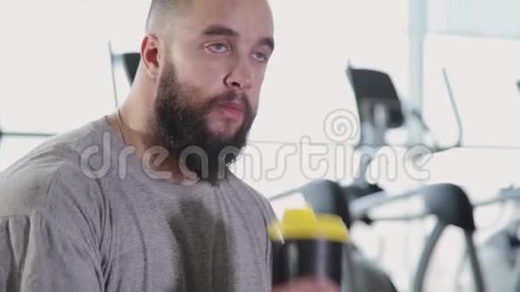 英俊的运动男子打开一个蛋白质摇床和饮料在健身房视频的预览图