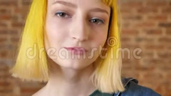 年轻女子转过头挥舞着她的黄色头发砖背景现代青年的亲密肖像视频的预览图