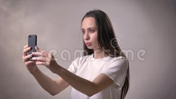 年轻的黑发女孩有一个视频电话智能手机沟通概念灰色背景视频的预览图