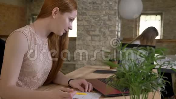 年轻快乐的姜女商人在办公室里用笔记本电脑工作把信息和文件进行比较工作理念视频的预览图