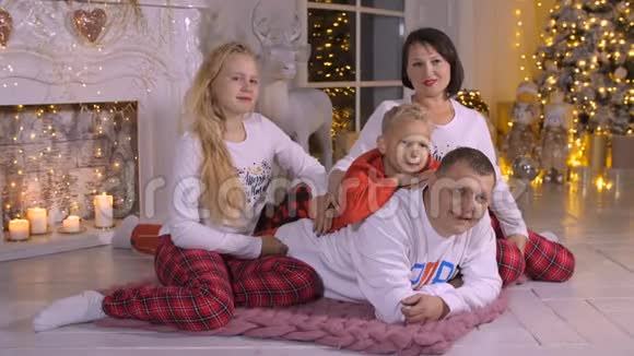 家庭爸爸妈妈女儿和儿子在圣诞树和壁炉的背景视频的预览图