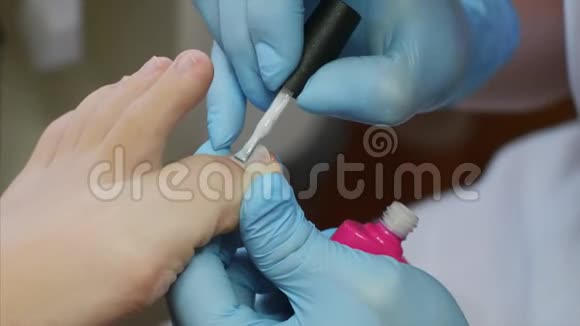 美容师用粉色皮肤紫胶在美容院涂脚趾甲视频的预览图