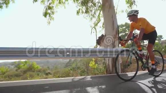 骑自行车的人沿着一条路上山后景夏日慢动作视频的预览图