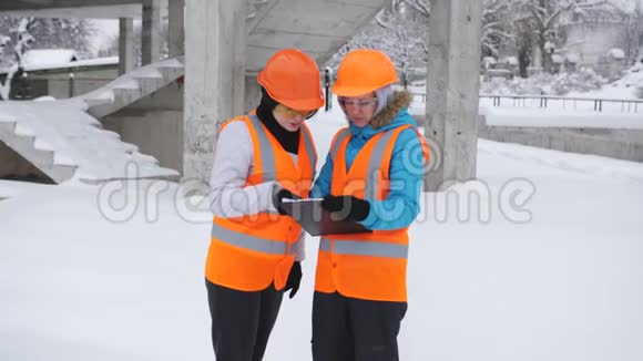 两名女检查员在冬季在施工现场检查和检查施工计划视频的预览图