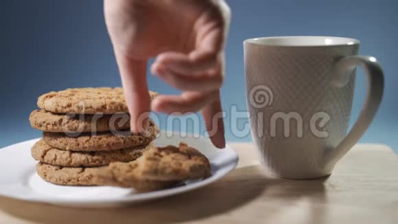 女性手在牛奶中蘸着巧克力饼干慢动作视频的预览图