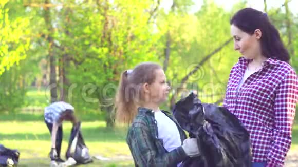 一位年轻女孩和一位青少年志愿者的画像他们手里拿着一个塑料袋手里拿着垃圾看着摄像机视频的预览图