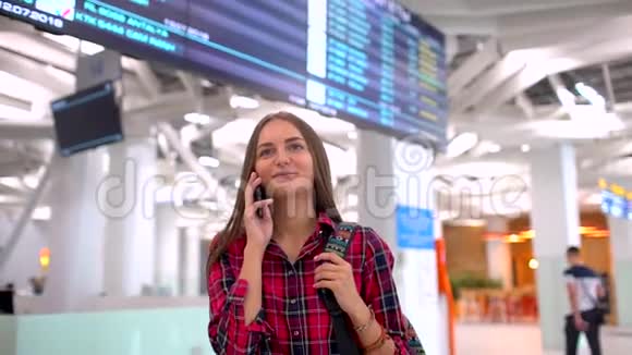 白人女性游客在机场使用智能手机在现代机场行走的年轻女子近距离拍摄视频的预览图