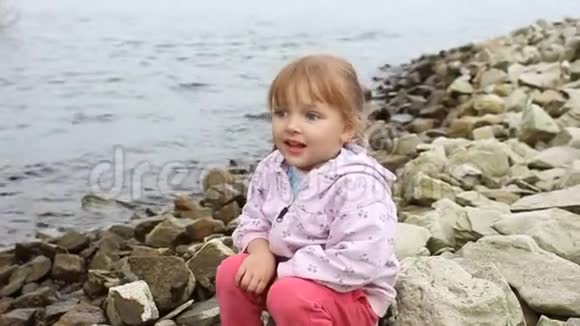 小女孩坐在河岸上视频的预览图