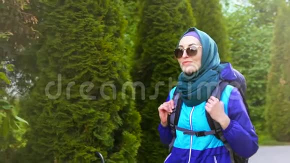 戴着头巾戴着眼镜背包的穆斯林美女的肖像用谈话和微笑视频的预览图