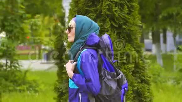 戴头巾的可爱女游客和带背包的太阳镜在公园散步视频的预览图