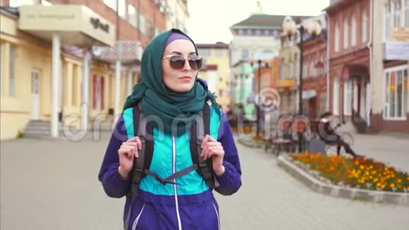 一个女游客戴着头巾背着墨镜背着背包走在街上视频的预览图