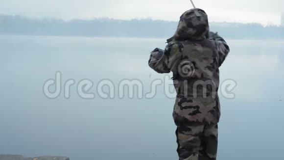 穿着迷彩服的女渔夫在一个初秋的早晨在雾中向河上扔了一根鱼竿视频的预览图