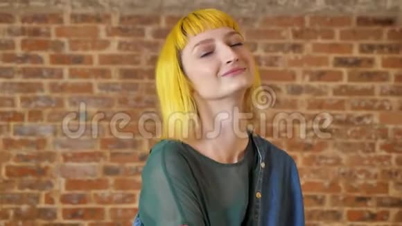 年轻漂亮的女人一头黄色的头发跳舞看着镜头在砖的背景上被孤立快乐微笑视频的预览图